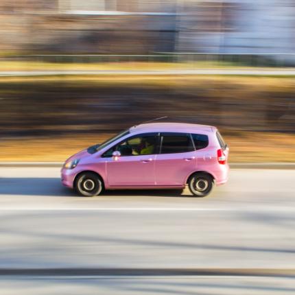 Photo d'une voiture rose circulant sur la chaussée