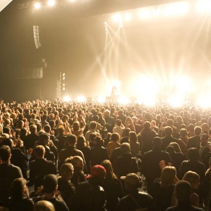 Photo d'un concert au zénith d'Amiens. On y voit la fosse pleine de spectateurs et les projecteurs éclairant la scène.